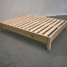 a wooden bed frame sitting on top of a gray floor