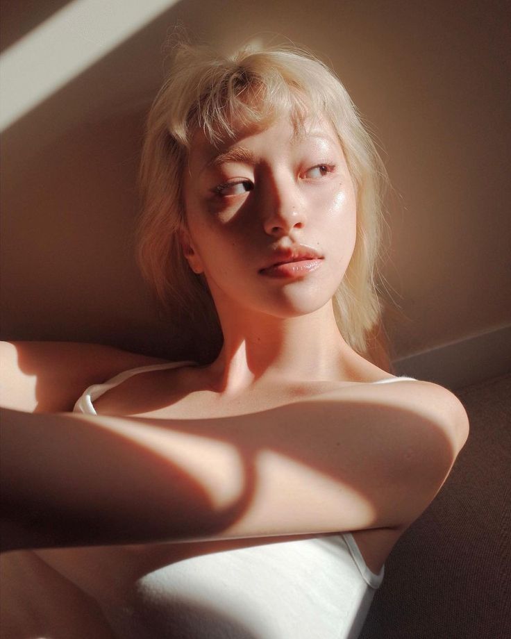 a woman with blonde hair is posing for a photo in white dress and sunlight coming through the window