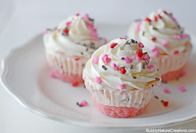 three cupcakes with white frosting and sprinkles on a plate