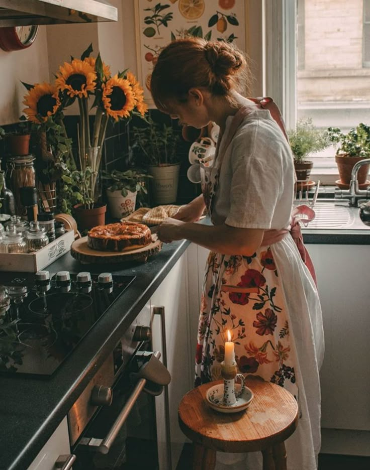 a woman standing in a kitchen preparing food on top of a counter next to a window