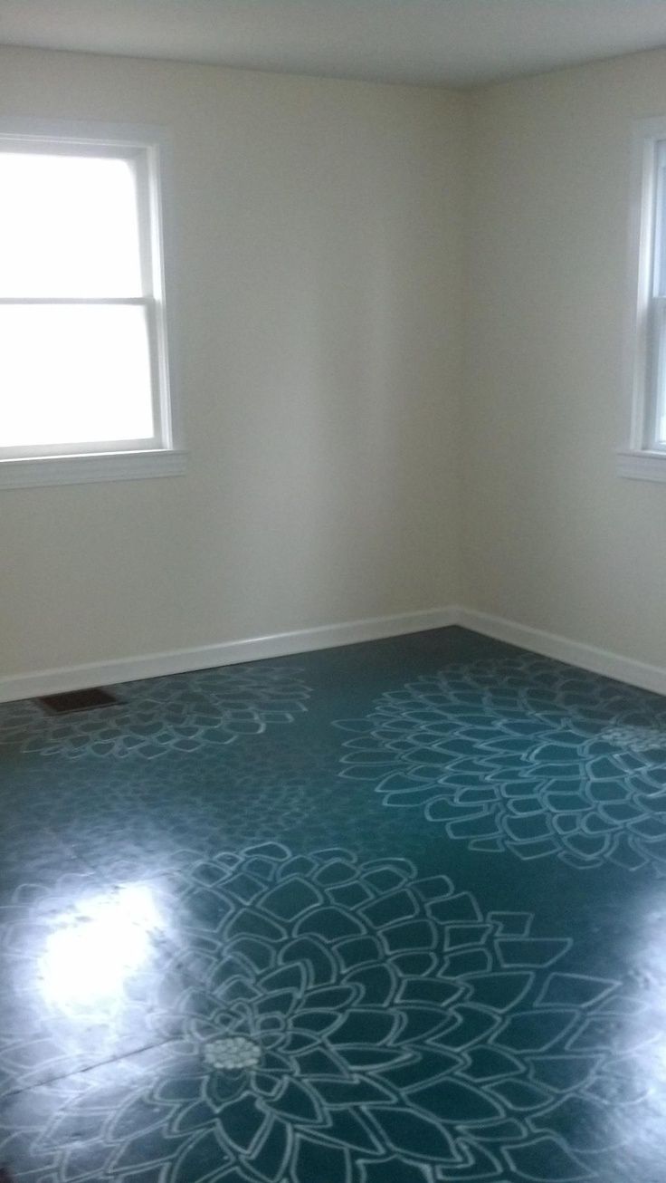 an empty room with two windows and a painted floor in the middle is pictured here