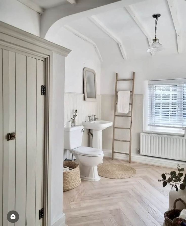 a bathroom with white walls and wooden floors