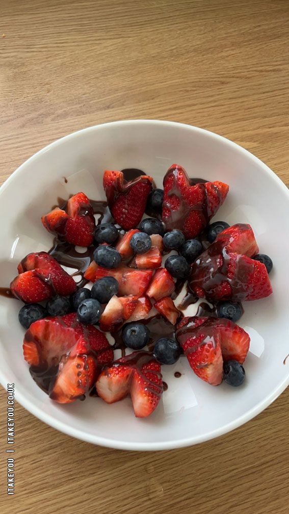 strawberries and blueberries are in a white bowl