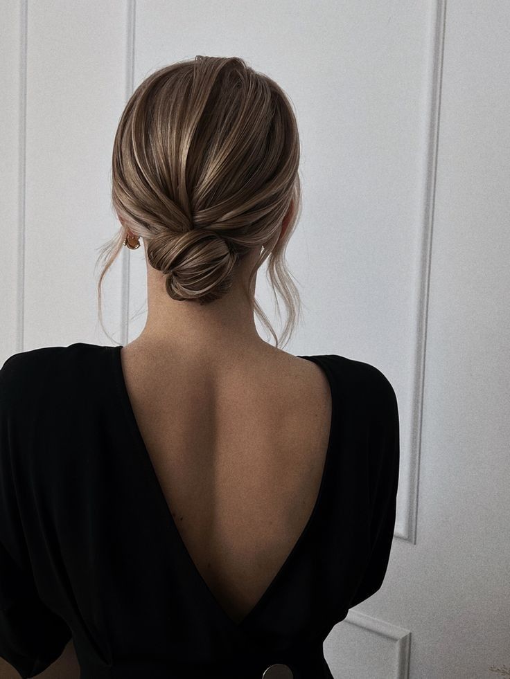 a woman with her back to the camera wearing a black dress and hair in a low bun