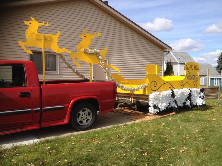 a red truck parked in front of a house with christmas decorations on the back of it