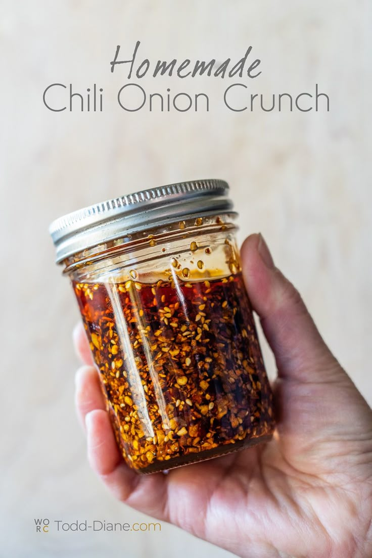 someone holding a jar filled with chili onion crunch