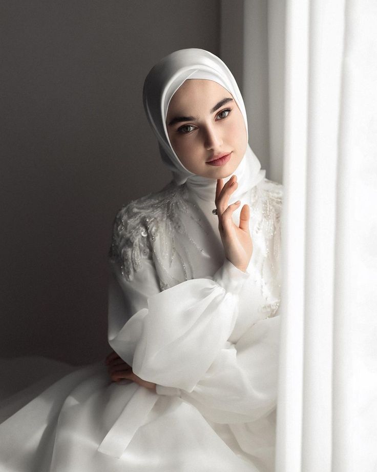 a woman wearing a white hijab is posing for a photo with her hands on her chin