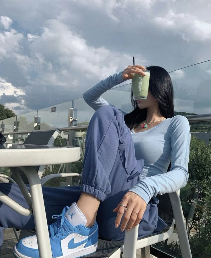 a woman sitting in a chair drinking from a cup