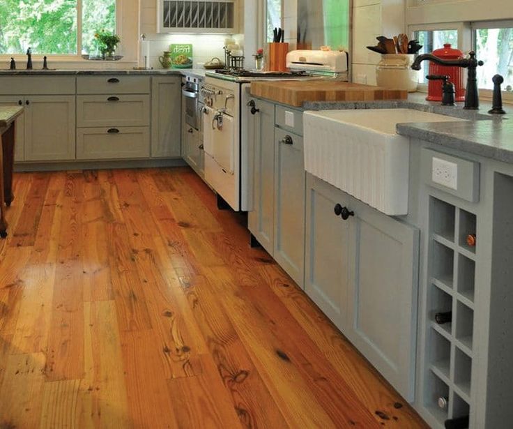 a large kitchen with wooden floors and white cabinets is pictured in this image from the front view