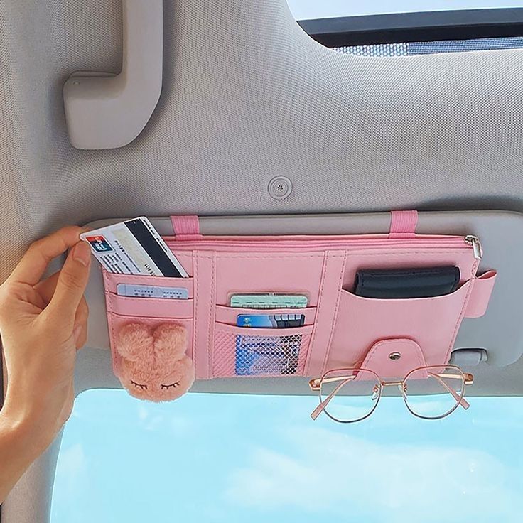 a pink purse hanging from the side of a car with sunglasses and money in it