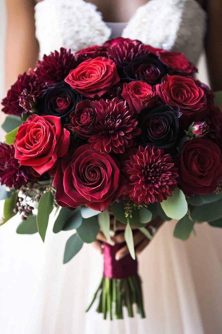 a bride holding a bouquet of red and black flowers