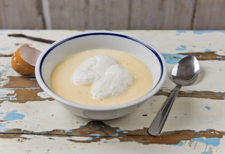 a white bowl filled with cream next to an egg on top of a wooden table