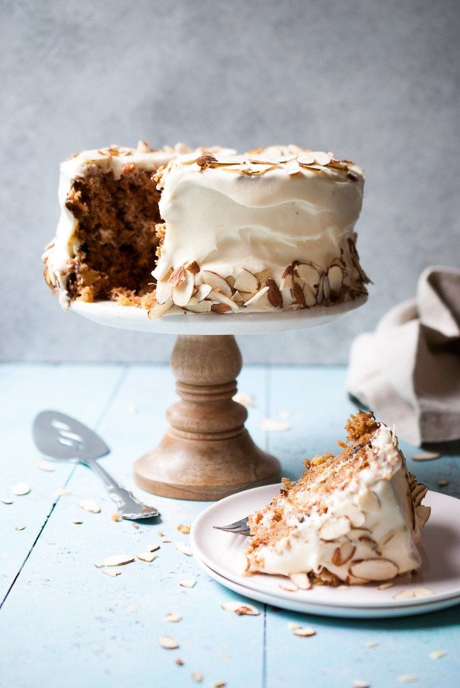 there is a piece of cake with white frosting and nuts on the plate next to it