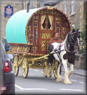 a horse pulling a carriage down the street in front of a car and another vehicle