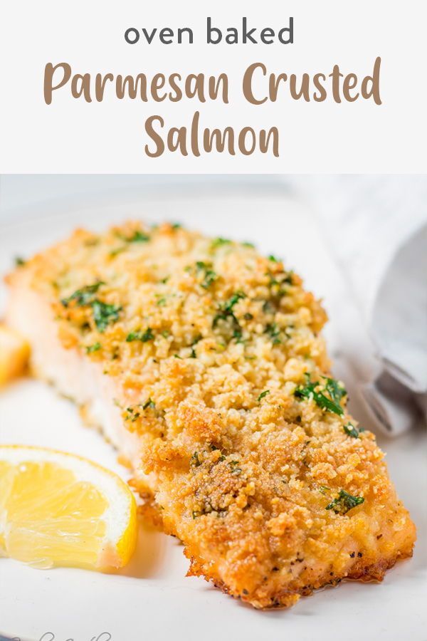 parmesan crusted salmon on a white plate with lemon wedges and breadcrumbs