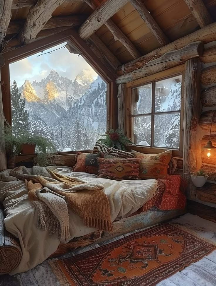 a bed sitting under a window in a bedroom next to a wooden floor covered in blankets