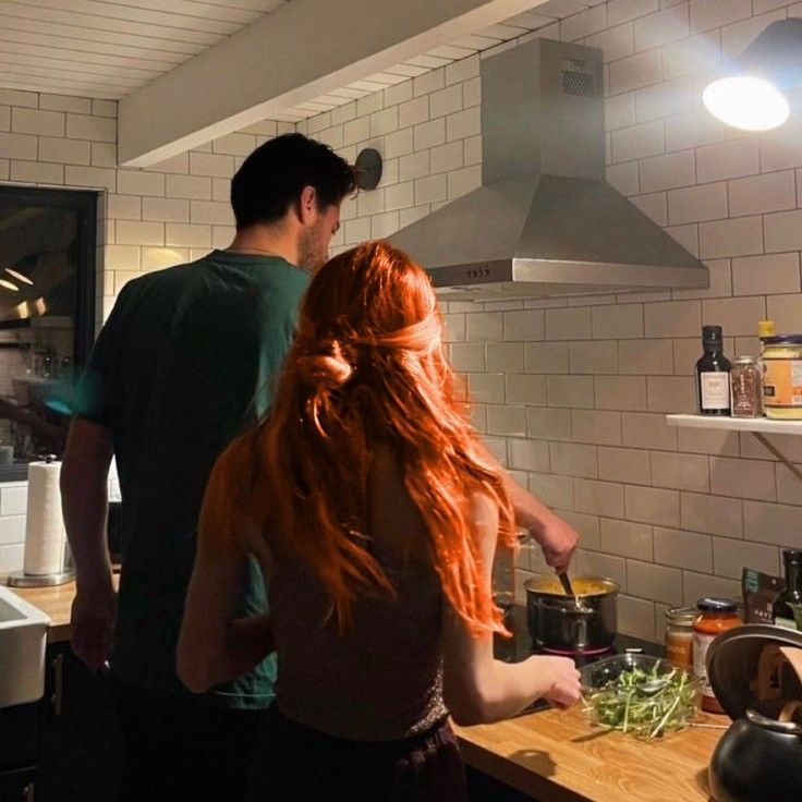 two people standing in a kitchen preparing food