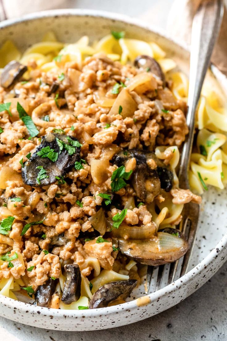 a bowl filled with pasta, meat and mushrooms