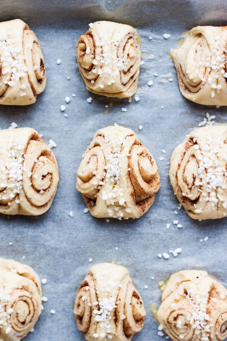 twelve cinnamon rolls on a baking sheet with sea salt sprinkled on top, ready to go into the oven