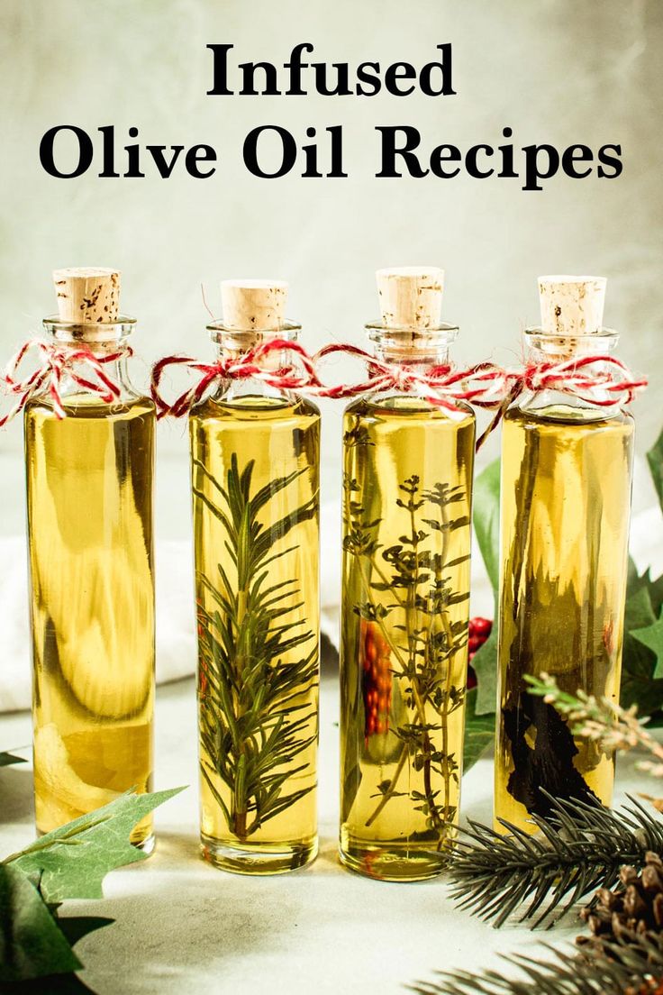 three bottles filled with olive oil next to pine cones