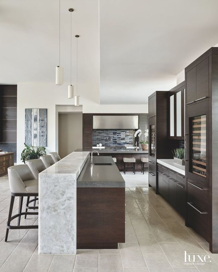 a large kitchen with marble counter tops and dark wood cabinets