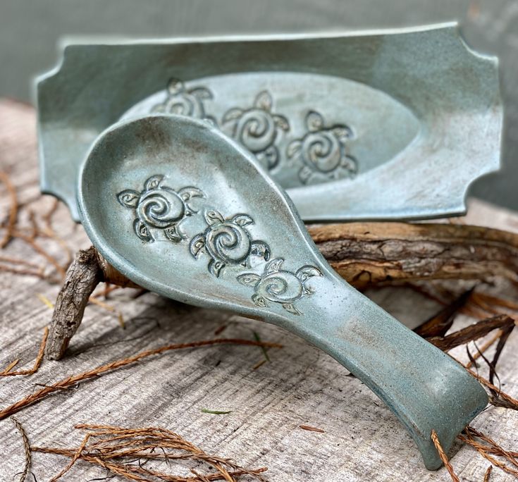 two metal spoons sitting on top of a piece of wood next to each other