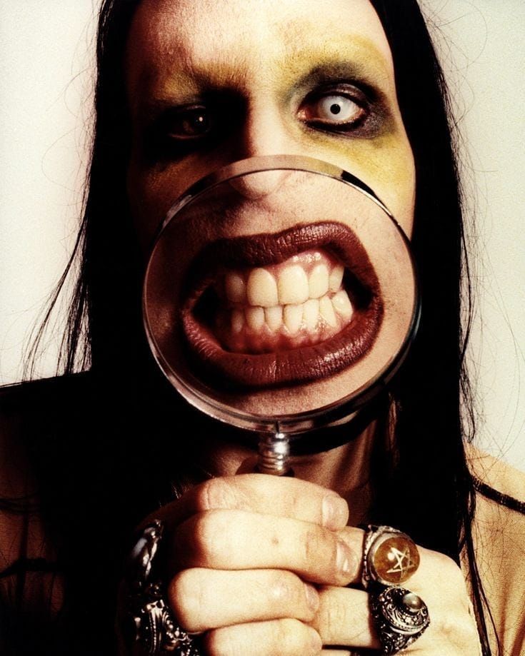 a woman holding a magnifying glass with her mouth open and teeth painted yellow