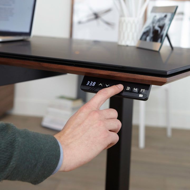 a hand is pressing the button on a keyboard that has been placed on top of a table