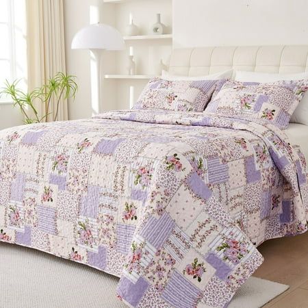 a bedroom with a bed covered in purple and white quilts