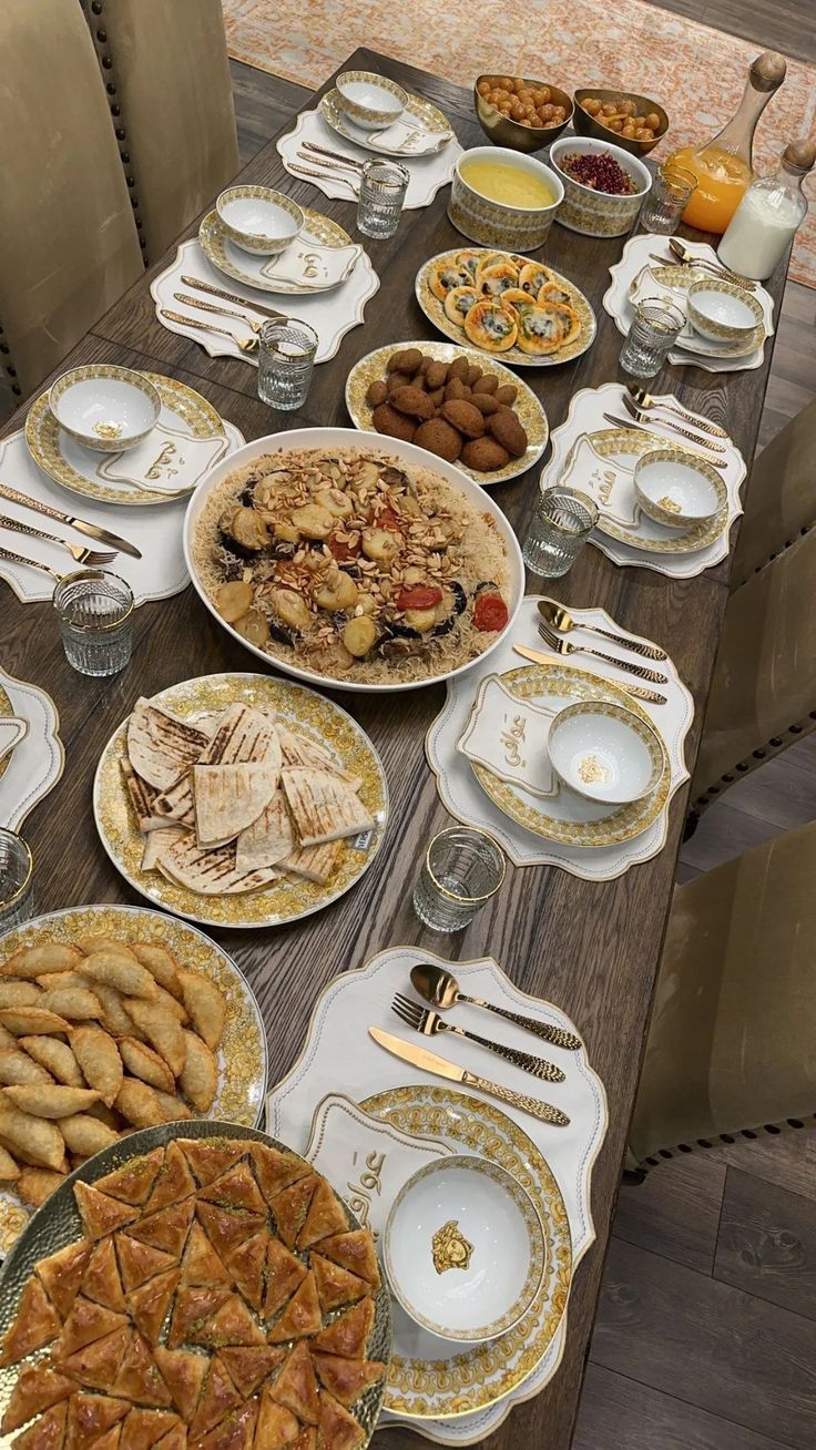 the table is set with many different types of food on plates and silver wares