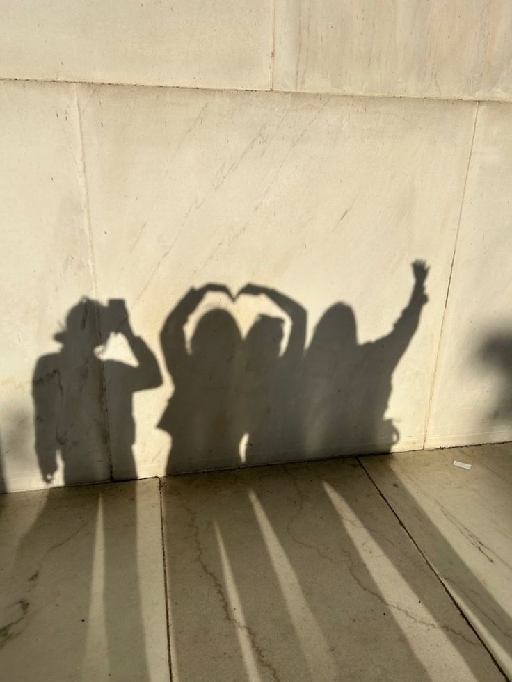 the shadow of two people standing in front of a wall with their hands on their head