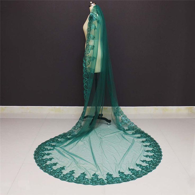 a dress on display in front of a wall with a green veil draped over it