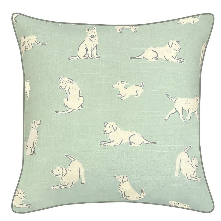 a green pillow with dogs on it and white outlines in the middle, sitting down