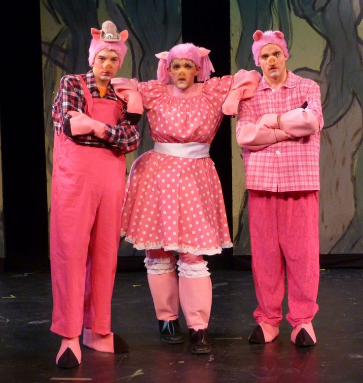 three people in pink costumes standing on a stage