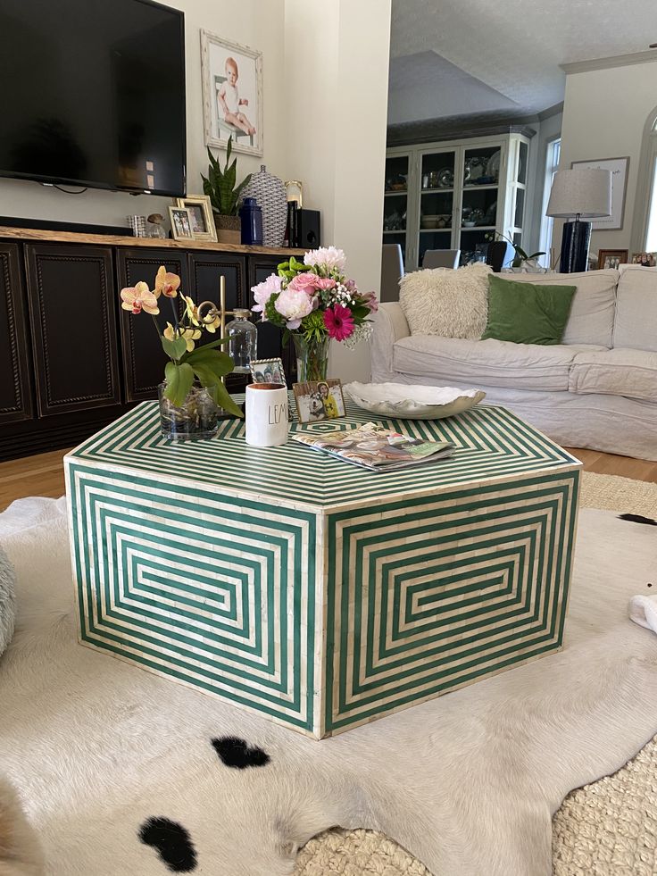 a green and white box sitting on top of a rug in front of a couch