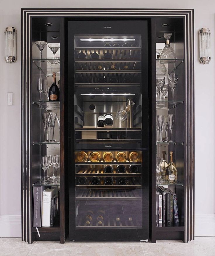 an open wine refrigerator with many bottles and glasses in it's glass door area