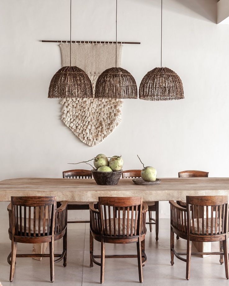 a dining room table with chairs and baskets hanging from it's ceiling over it