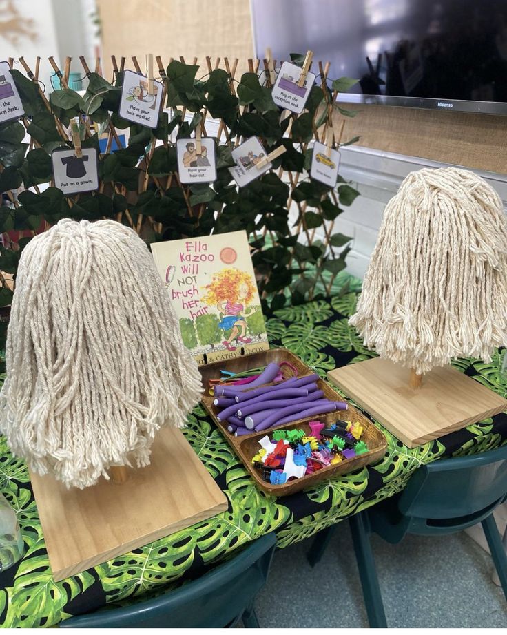 two white mop heads sitting on top of wooden trays filled with colorful beads