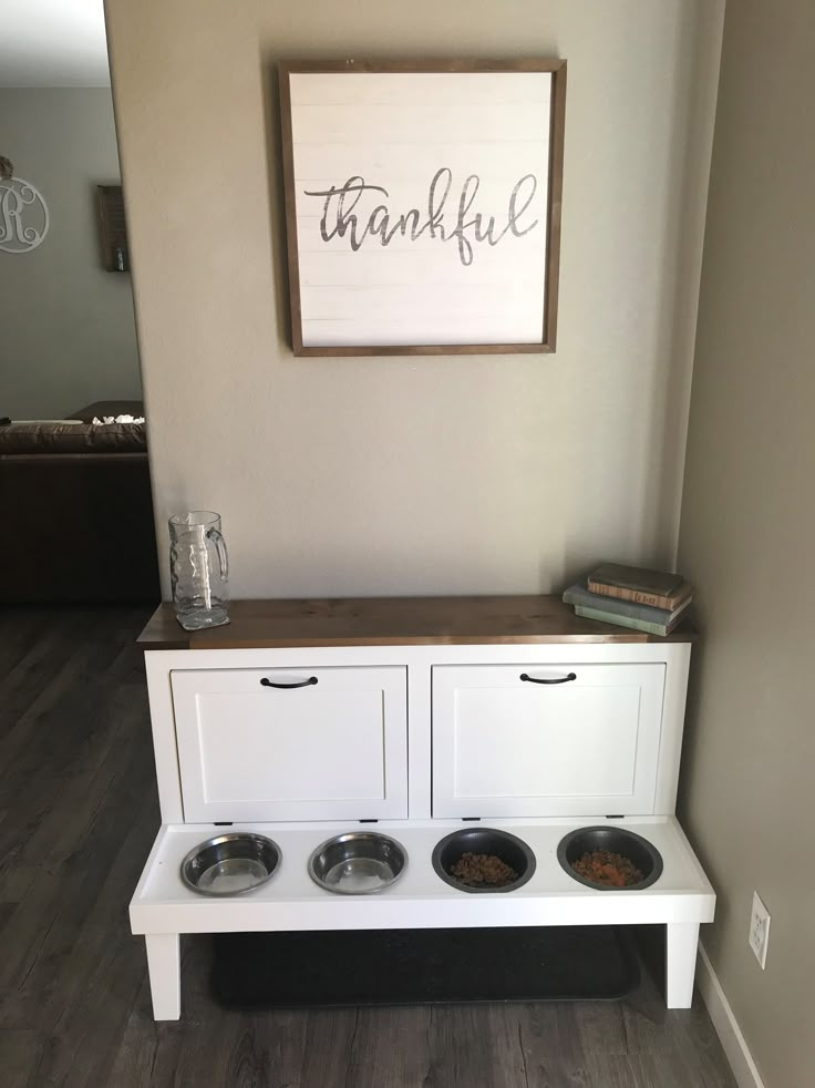 a white dog bowl stand with three bowls on it and a thank you sign above