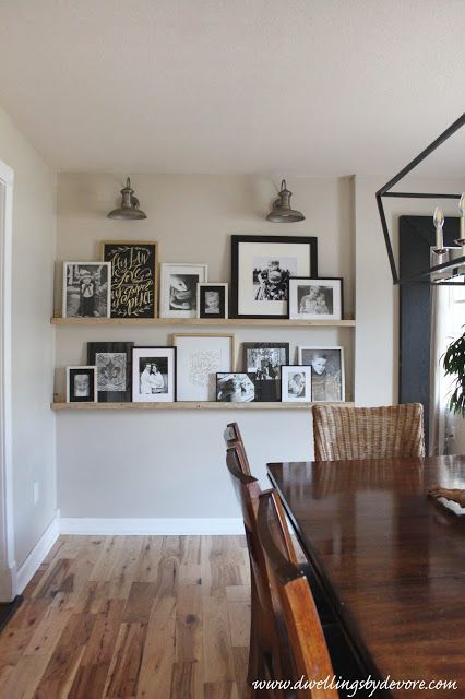 a dining room table with chairs and pictures on the wall