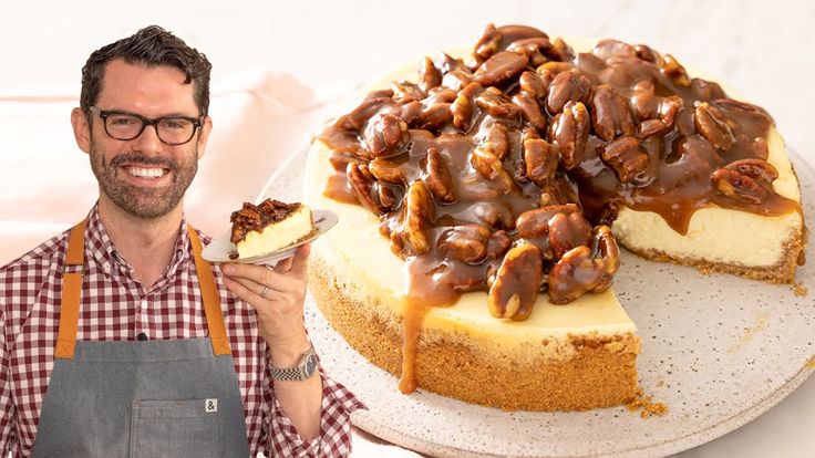 a man standing next to a cheesecake with chocolate toppings on it and holding a plate