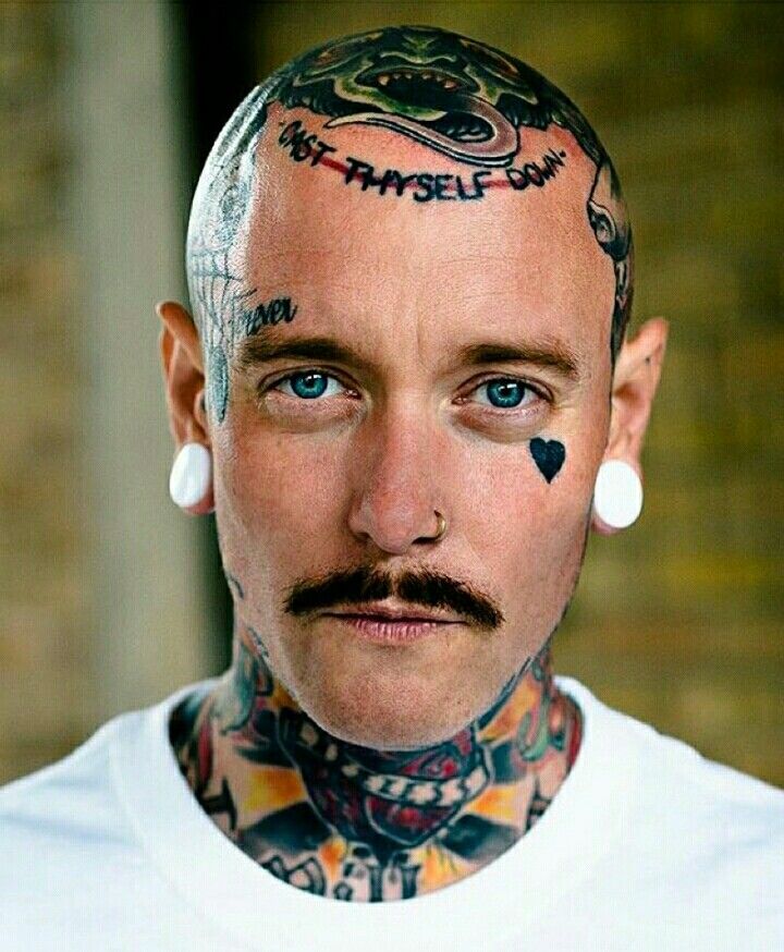 a man with tattoos and piercings on his head