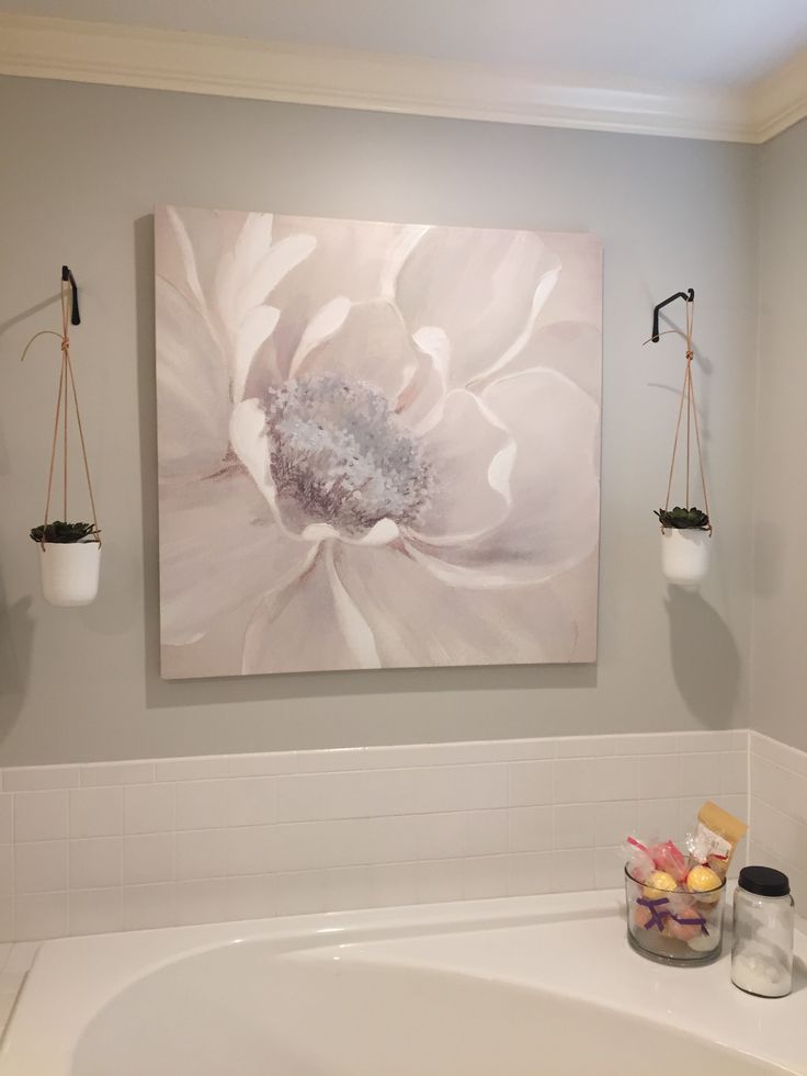 a bath room with a tub and a painting hanging on the wall next to it