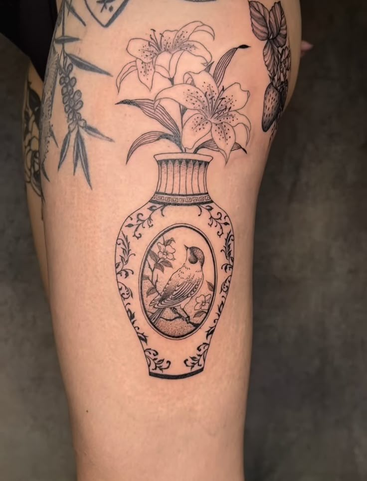 a woman's thigh with flowers in a vase tattoo