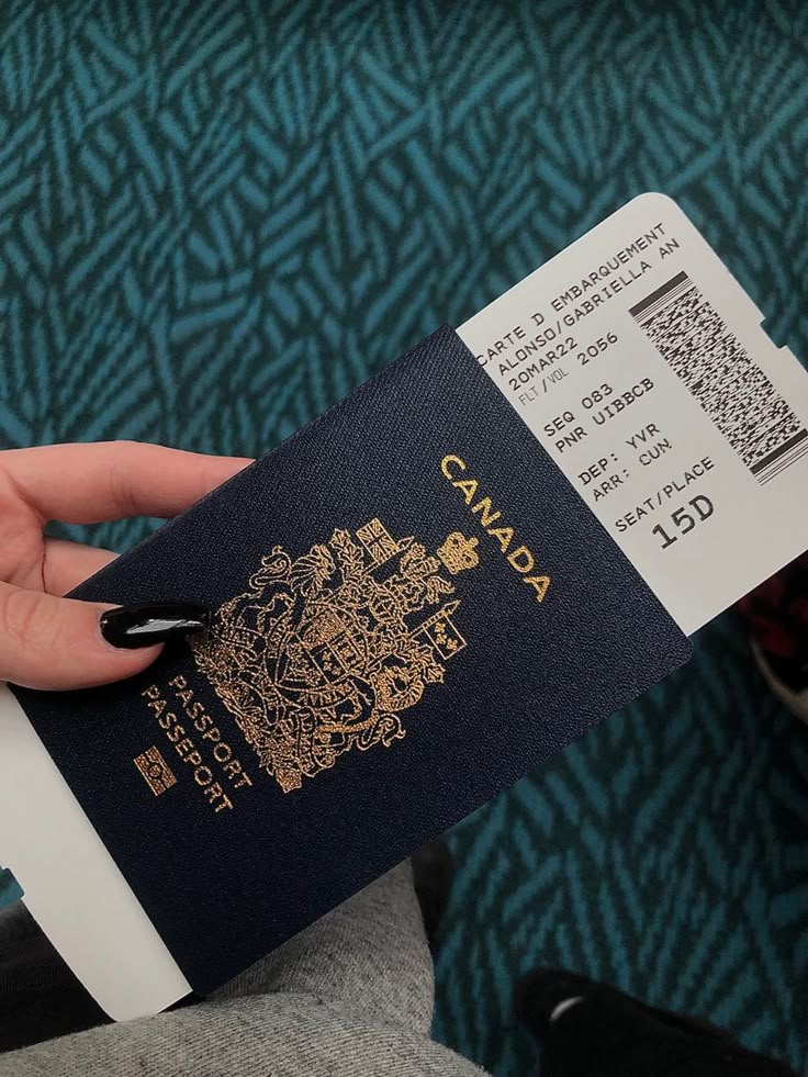 a person holding a canadian passport in their left hand and a boarding card in the other