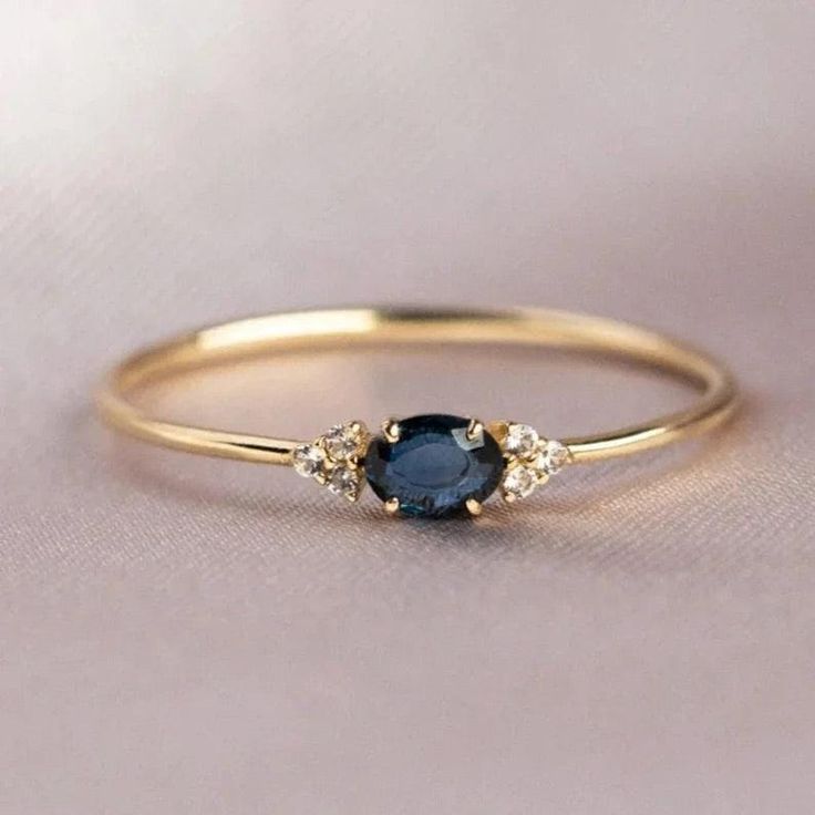 a gold ring with an oval blue stone and three small white diamonds on the side