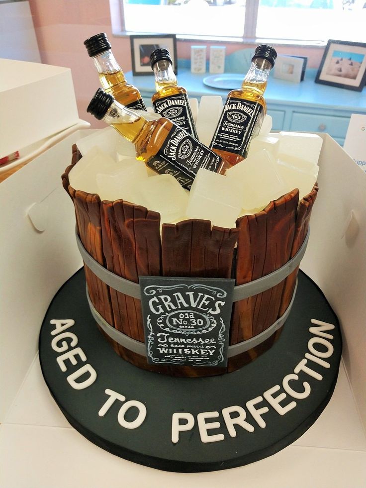 a birthday cake made to look like a barrel with three bottles of whiskey in it