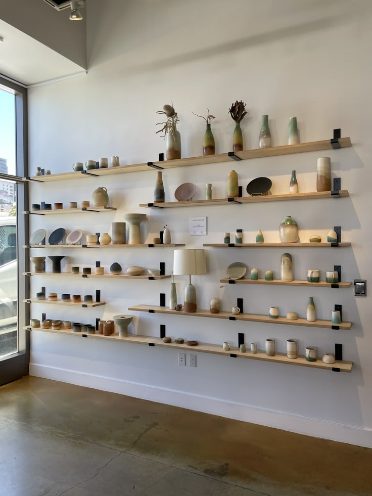 the shelves are filled with pottery and vases