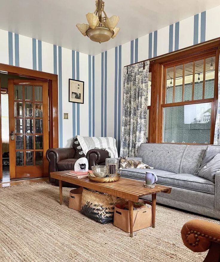 a living room with blue and white striped walls, two couches and a coffee table