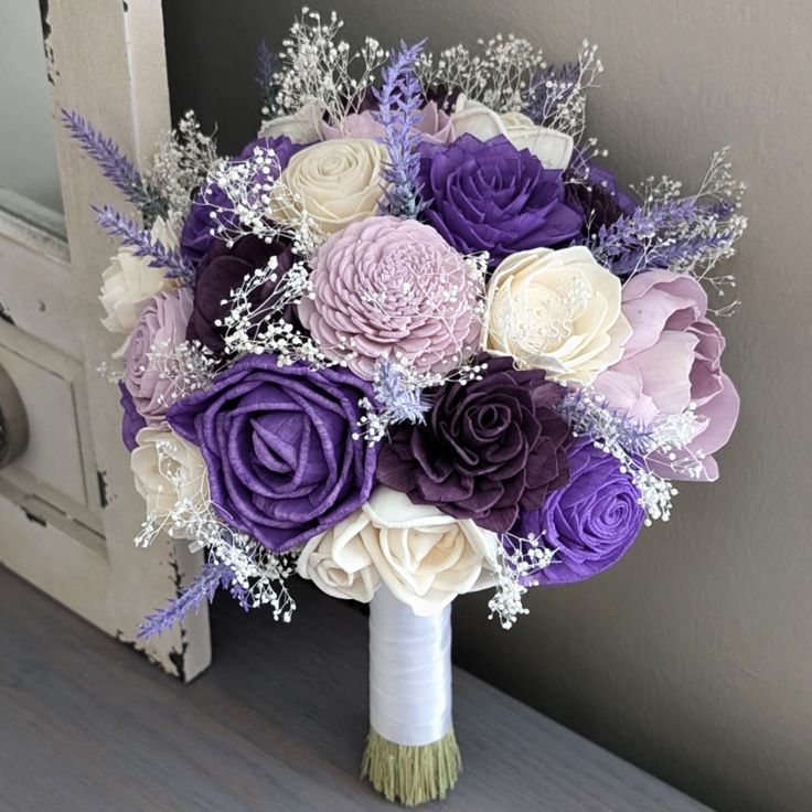 a bridal bouquet with purple and white flowers in front of an open door,